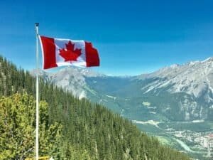 Canada Flag With Mountain Range View Canada Is Canada Expensive to Visit? Canada Travel Cost & Budget Guide 2026 Canada Flag With Mountain Range View, Canada