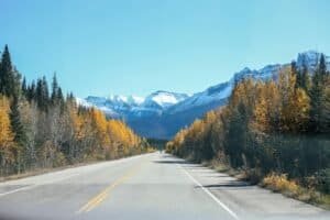 Road among trees against snowy mountains Canada Is Canada Expensive to Visit? Canada Travel Cost & Budget Guide 2026 Road among trees against snowy mountains, Canada