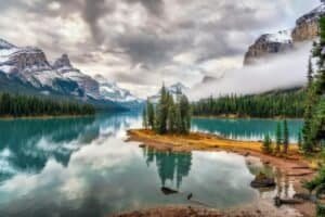 View of the Snow Capped Mountain from the River Under Cloudy Sky, Jasper, Canada