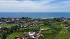 A beautiful aerial view of a village on Bali's coastline with lush greenery and the ocean in the background, Bali