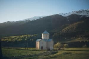 A serene church set against a majestic mountain backdrop in a rural landscape, Georgia