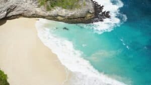 A stunning aerial view of a pristine beach with turquoise waters and a rocky coastline, Bali