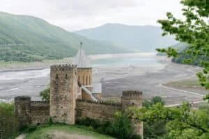 A stunning medieval castle overlooks a vast reservoir among lush green hills. Georgia