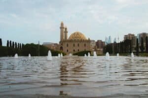 A stunning view of Baku's Taza Pir Mosque with fountain reflections and modern skyline in the background, Azerbaijan
