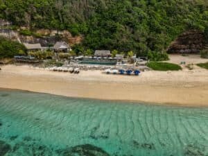 Aerial photo of a picturesque beachfront resort in Bali, showcasing clear waters and lush greenery