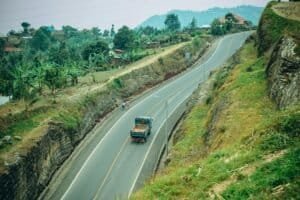 Aerial view of a rural road with a truck passing, surrounded by lush greenery, Rwanda