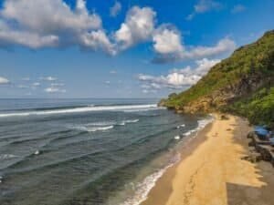 Explore the serene beauty of a Bali beach with azure waters golden sands and lush cliffs Bali Budget Travel Guide 2026: Travel Bali Cheap Under $50/Day Explore the serene beauty of a Bali beach with azure waters, golden sands, and lush cliffs