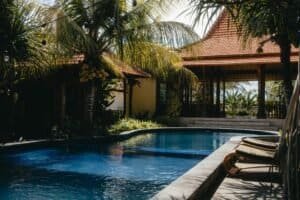 Relax by a luxurious tropical pool surrounded by lush palm trees under a sunny sky, perfect for summer getaways. Bali