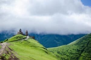 Scenic view of Gergeti Trinity Church atop green hills in Georgia