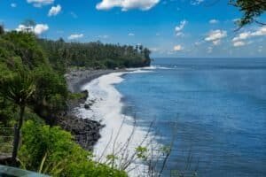 Serene view of Bali's rocky coastline with lush greenery and blue ocean, Bali